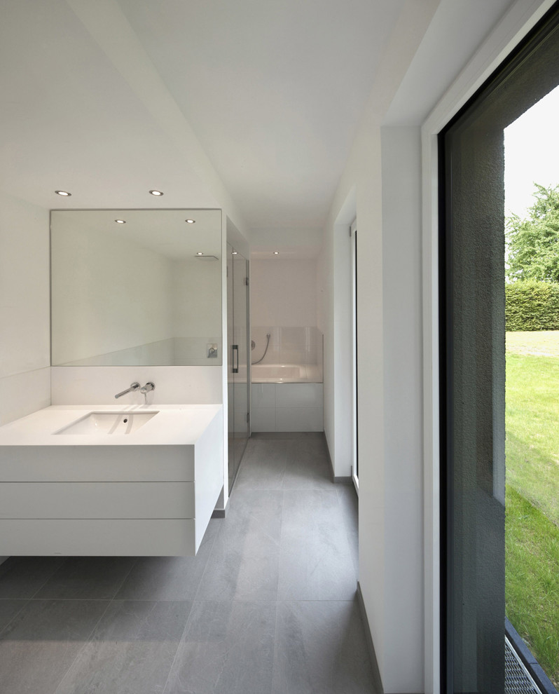 This is an example of a large contemporary bathroom in Dusseldorf with flat-panel cabinets, white cabinets, an alcove tub, a curbless shower, white tile, white walls, slate floors and an undermount sink.