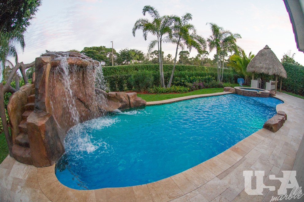 Large mediterranean backyard kidney-shaped aboveground pool in Miami with a water feature and natural stone pavers.