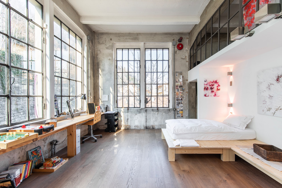 Large industrial master bedroom in Milan with dark hardwood floors, brown floor and grey walls.