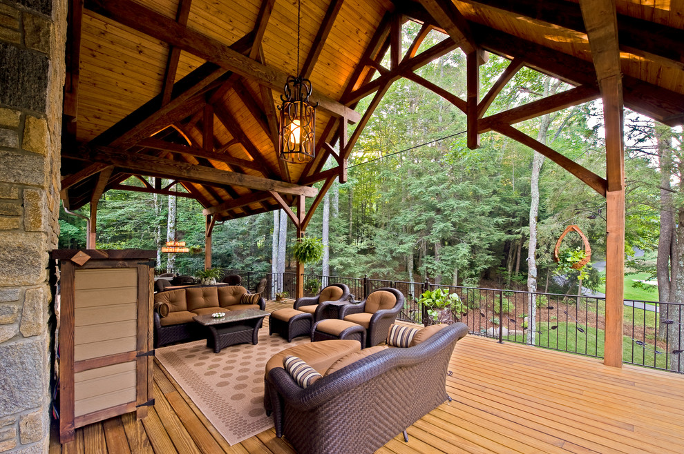 This is an example of an expansive country backyard deck in Charlotte with a roof extension.