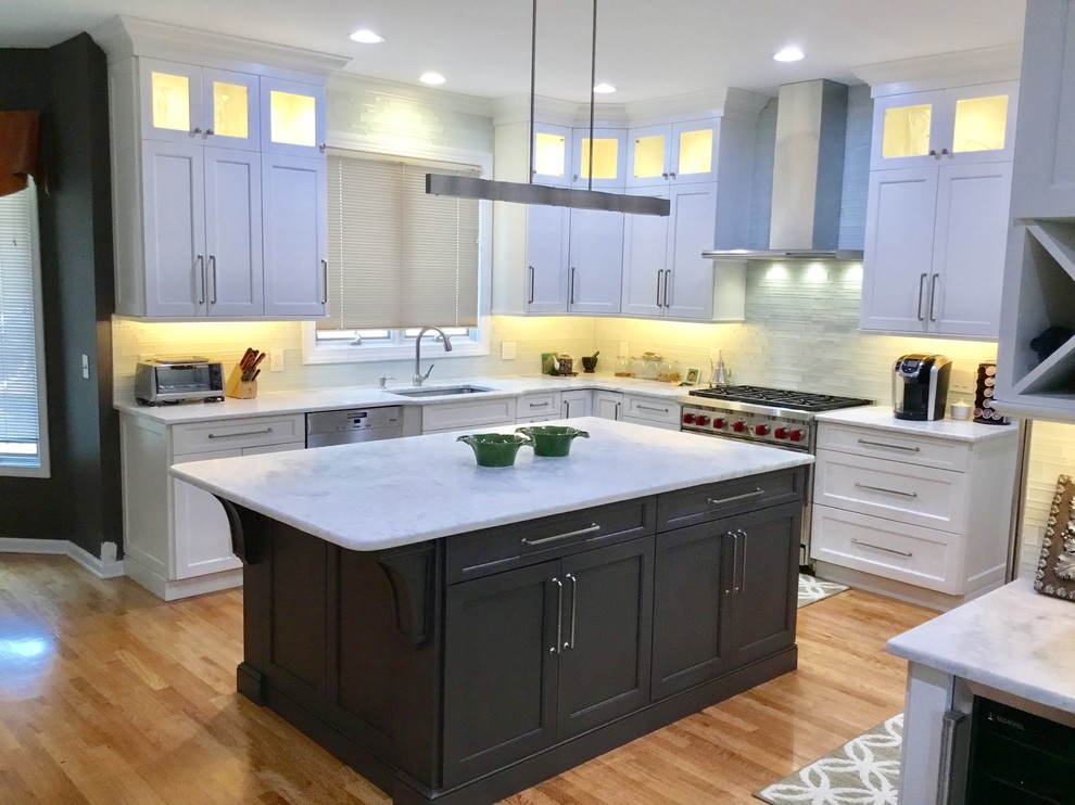 Example of a large transitional u-shaped light wood floor and beige floor open concept kitchen design in New York with an undermount sink, beaded inset cabinets, white cabinets, marble countertops, white backsplash, stainless steel appliances and an island