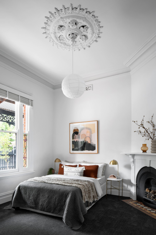 Design ideas for a traditional master bedroom in Melbourne with white walls, carpet, a corner fireplace, a wood fireplace surround and black floor.