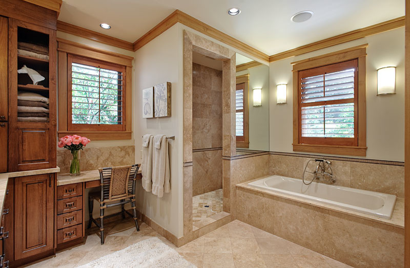 This is an example of an arts and crafts master bathroom in Seattle with raised-panel cabinets, medium wood cabinets, a drop-in tub, an alcove shower, beige tile, stone tile, beige walls, limestone floors and limestone benchtops.