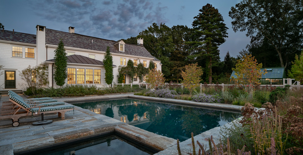 Modelo de piscina natural grande rectangular en patio trasero con paisajismo de piscina y adoquines de piedra natural