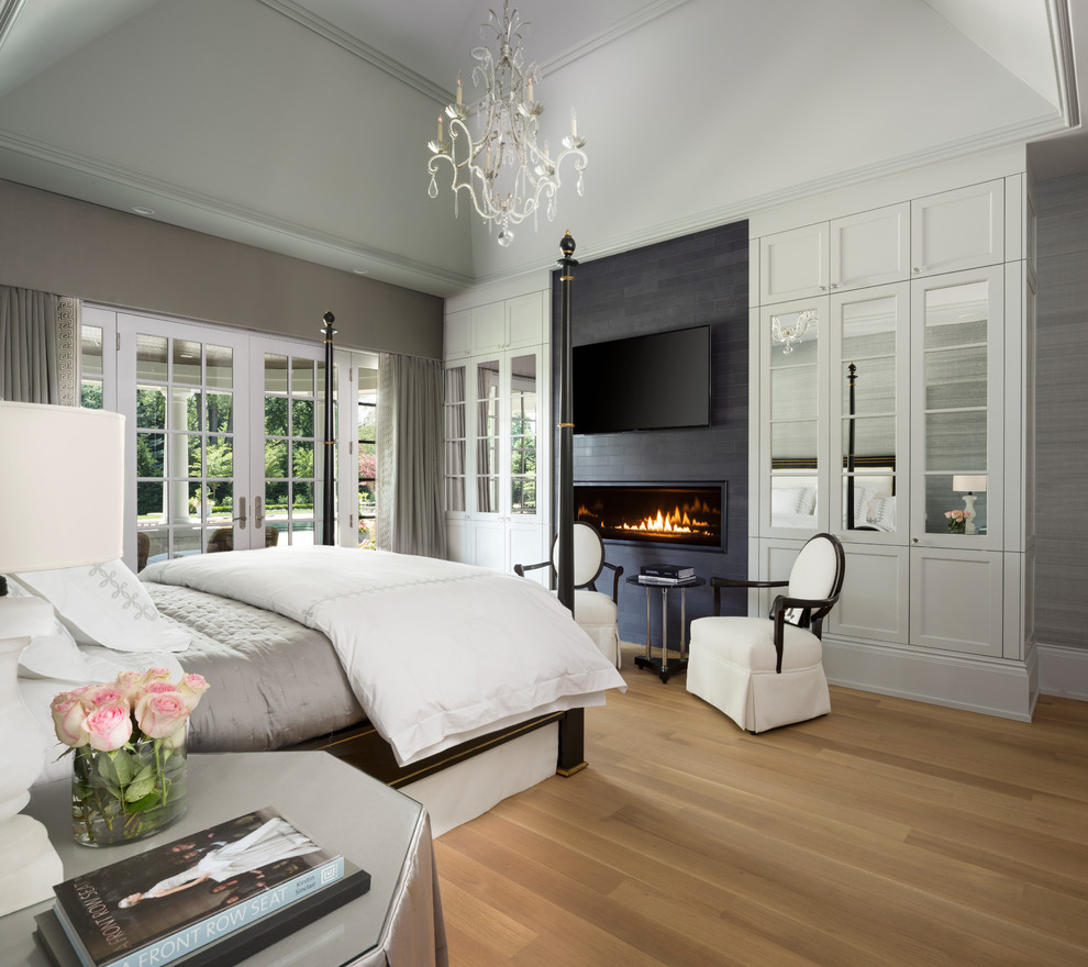 Inspiration for a transitional master bedroom in Detroit with grey walls, light hardwood floors, a ribbon fireplace, a tile fireplace surround and beige floor.
