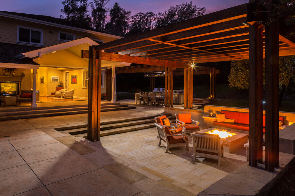This is an example of a large arts and crafts backyard patio in San Francisco with a fire feature, natural stone pavers and a pergola.