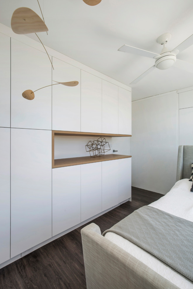 Idee per una camera degli ospiti minimalista di medie dimensioni con pareti bianche, parquet scuro, pavimento marrone e pareti in mattoni