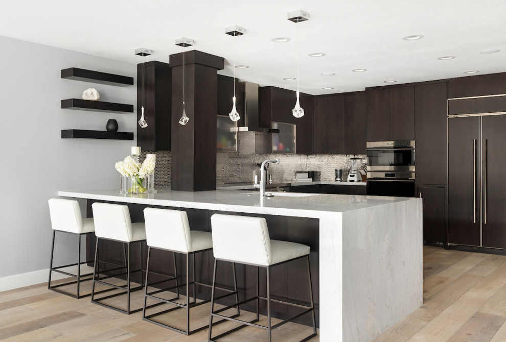 Inspiration for a mid-sized contemporary u-shaped kitchen in Salt Lake City with a single-bowl sink, flat-panel cabinets, brown cabinets, metallic splashback, metal splashback, panelled appliances, light hardwood floors, a peninsula and white benchtop.