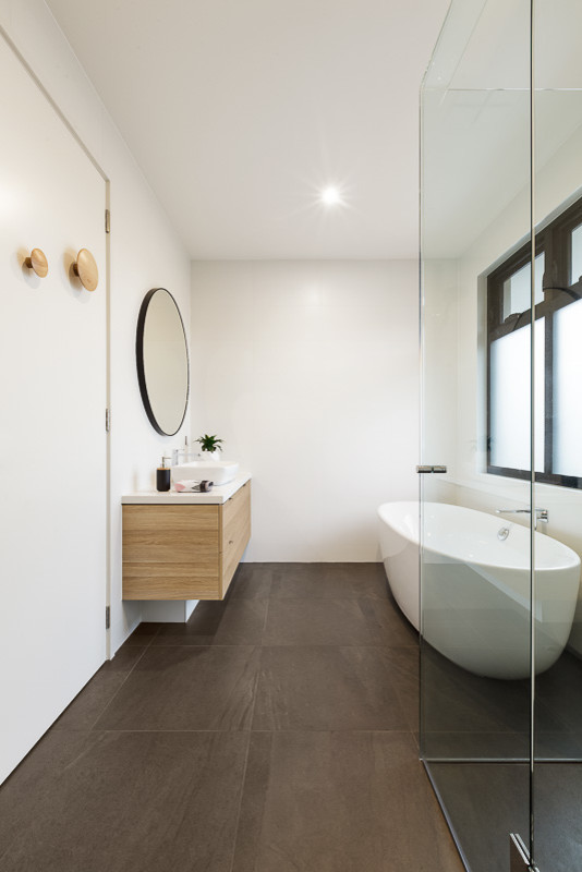 This is an example of a scandinavian master bathroom in Melbourne with flat-panel cabinets, light wood cabinets, a freestanding tub, white walls, porcelain floors, a vessel sink, engineered quartz benchtops, a corner shower, grey floor and a hinged shower door.