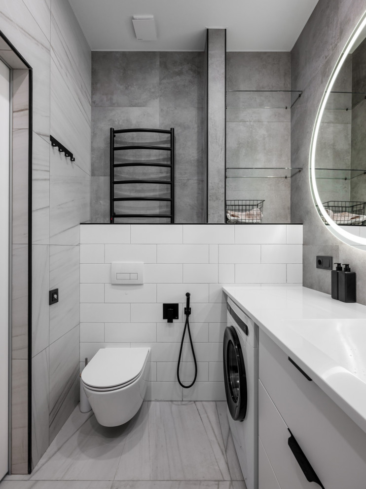 Idéer för små funkis en-suite badrum, med släta luckor, vita skåp, ett badkar i en alkov, en dusch/badkar-kombination, en vägghängd toalettstol, vit kakel, vita väggar, ett integrerad handfat och grått golv