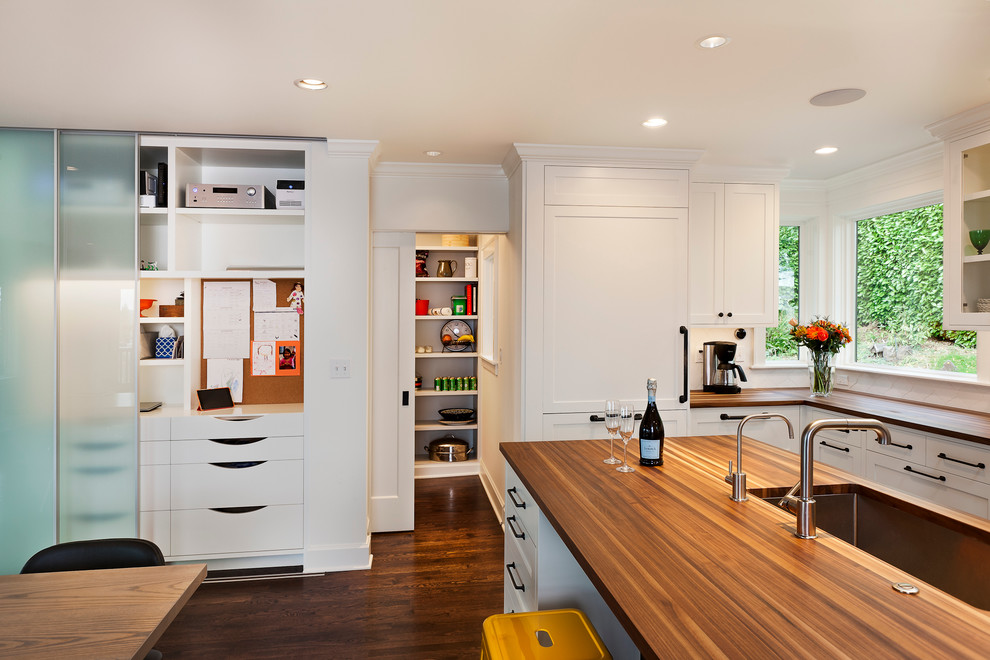 Inspiration for a mid-sized transitional u-shaped dark wood floor and brown floor eat-in kitchen remodel in Seattle with an undermount sink, recessed-panel cabinets, white cabinets, wood countertops, white backsplash, ceramic backsplash, stainless steel appliances and an island