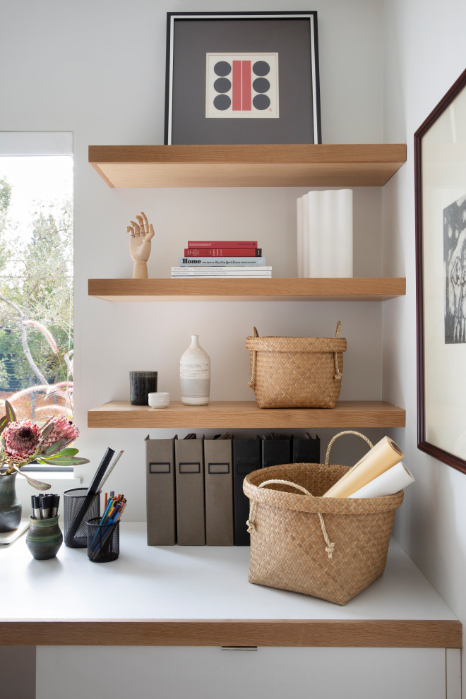 Inspiration för mellanstora minimalistiska hemmabibliotek, med vita väggar, ljust trägolv, ett inbyggt skrivbord och brunt golv