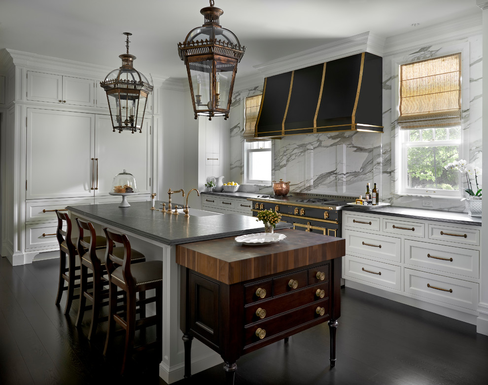 Inspiration for a traditional l-shaped kitchen in Chicago with a farmhouse sink, soapstone benchtops, white splashback, stone slab splashback, panelled appliances, with island, recessed-panel cabinets, white cabinets, dark hardwood floors and black floor.