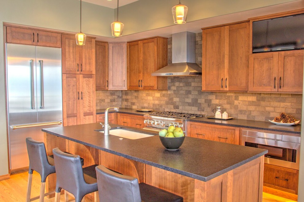 Large mountain style l-shaped light wood floor and brown floor open concept kitchen photo with an undermount sink, quartzite countertops, stainless steel appliances, an island, shaker cabinets, dark wood cabinets, brown backsplash and ceramic backsplash