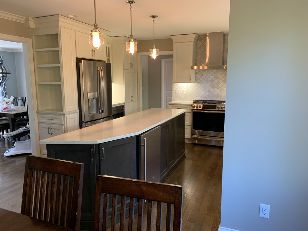Inspiration for a mid-sized transitional l-shaped medium tone wood floor and brown floor eat-in kitchen remodel in Cincinnati with an undermount sink, flat-panel cabinets, white cabinets, quartz countertops, white backsplash, marble backsplash, stainless steel appliances, an island and white countertops