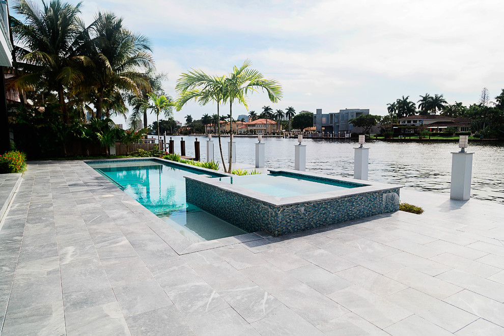 Inspiration for a mid-sized modern backyard custom-shaped pool in Miami with a hot tub.