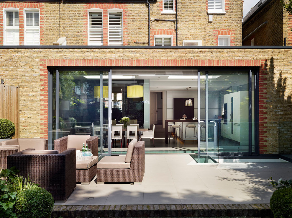 Design ideas for a mid-sized contemporary backyard patio in London with tile and no cover.