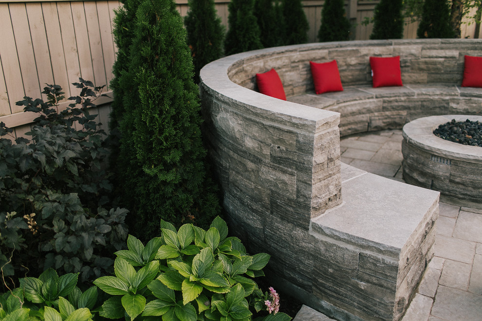 Photo of a mid-sized traditional backyard patio in Toronto with a fire feature, concrete pavers and no cover.