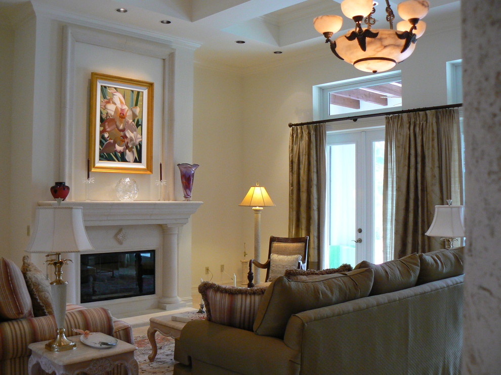 Example of a large island style formal and enclosed travertine floor living room design in Miami with beige walls, a standard fireplace and a stone fireplace
