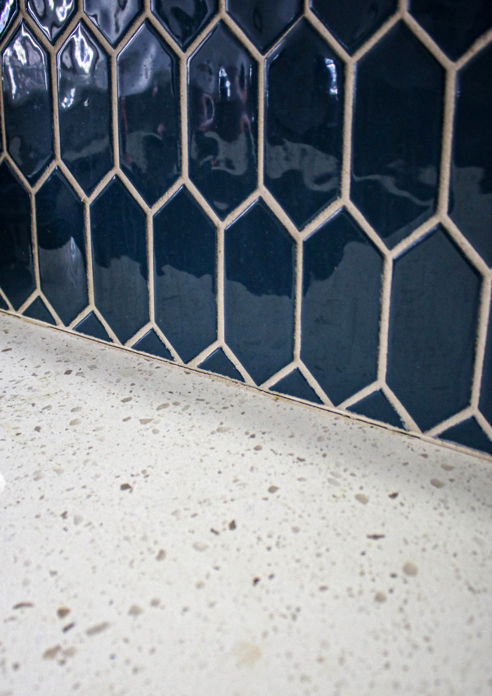 Стильный дизайн: маленькая отдельная, прямая прачечная в стиле неоклассика (современная классика) с врезной мойкой, фасадами с выступающей филенкой, белыми фасадами, столешницей из кварцевого агломерата, синим фартуком, фартуком из цементной плитки, серыми стенами, со стиральной и сушильной машиной рядом и белой столешницей для на участке и в саду - последний тренд