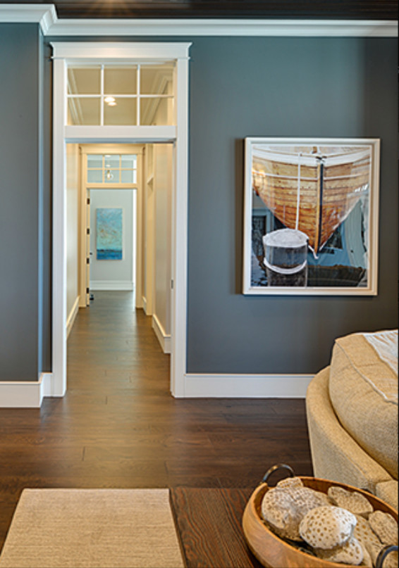 Large transitional walk-out dark wood floor and brown floor basement photo with blue walls, a standard fireplace and a stone fireplace