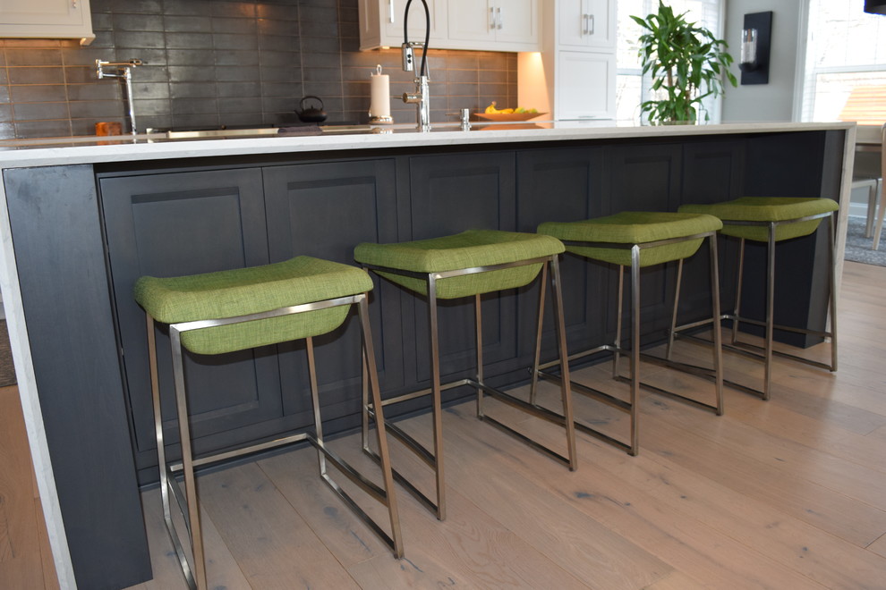 Eat-in kitchen - large transitional l-shaped light wood floor and multicolored floor eat-in kitchen idea in Chicago with beaded inset cabinets, white cabinets, quartz countertops, black backsplash, ceramic backsplash, stainless steel appliances and an island