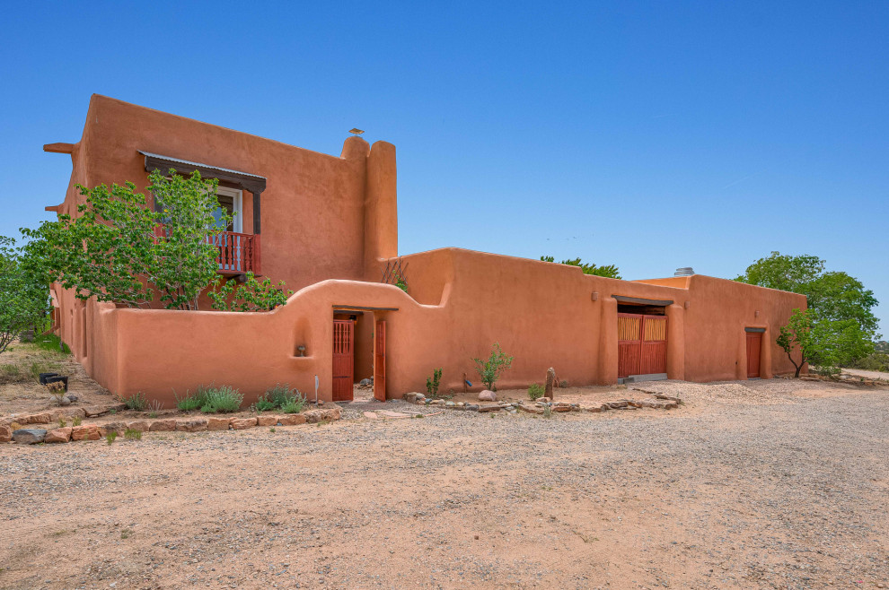 Photo of an expansive two-storey adobe orange house exterior in Other with a flat roof.