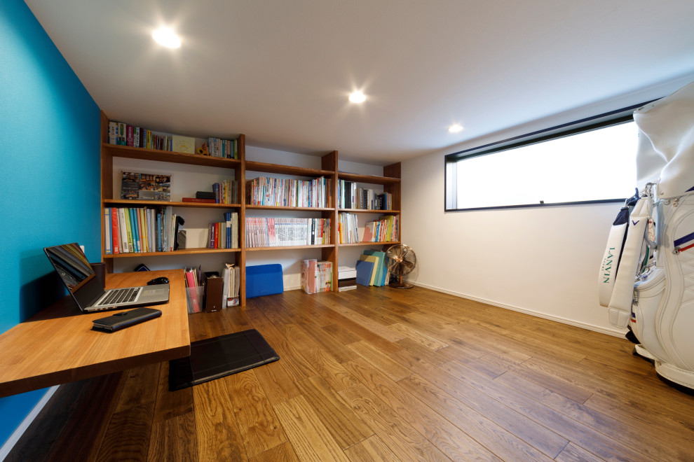 Inspiration för arbetsrum, med ett bibliotek, blå väggar, mellanmörkt trägolv, ett inbyggt skrivbord och brunt golv