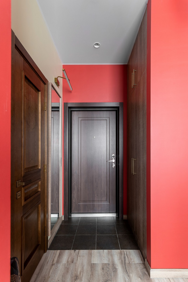 Immagine di un corridoio moderno di medie dimensioni con pareti rosse, pavimento in vinile, una porta singola, una porta in legno scuro, pavimento marrone e carta da parati