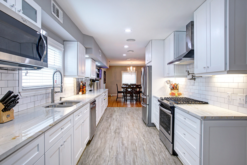 Inspiration for a mid-sized transitional galley eat-in kitchen in Houston with a double-bowl sink, shaker cabinets, white cabinets, marble benchtops, white splashback, subway tile splashback, stainless steel appliances, porcelain floors, no island and grey floor.