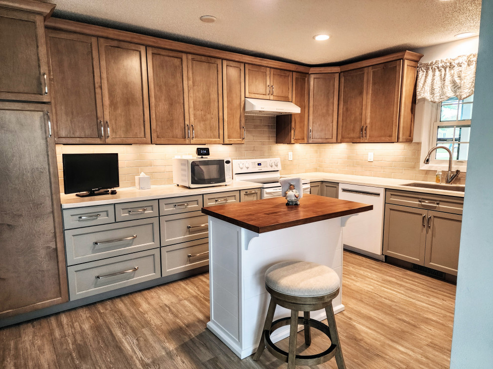 Inspiration for a mid-sized transitional l-shaped vinyl floor and multicolored floor eat-in kitchen remodel with an undermount sink, shaker cabinets, solid surface countertops, beige backsplash, subway tile backsplash, white appliances, an island and white countertops