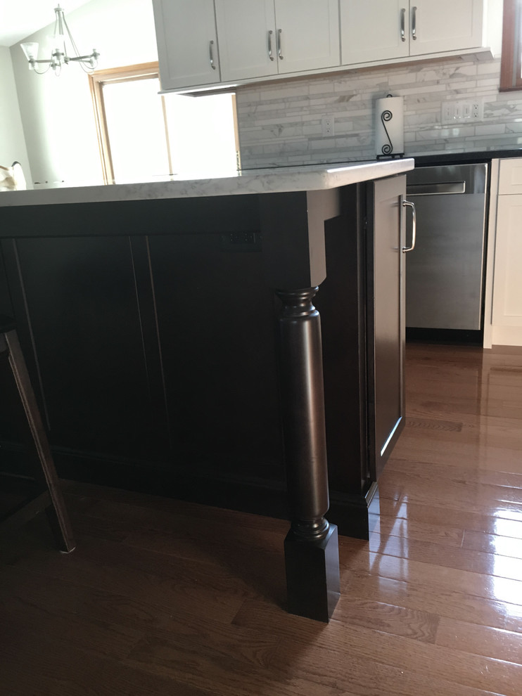 Inspiration for a large transitional single-wall medium tone wood floor eat-in kitchen remodel with an undermount sink, shaker cabinets, white cabinets, granite countertops, multicolored backsplash, marble backsplash, stainless steel appliances, an island and black countertops