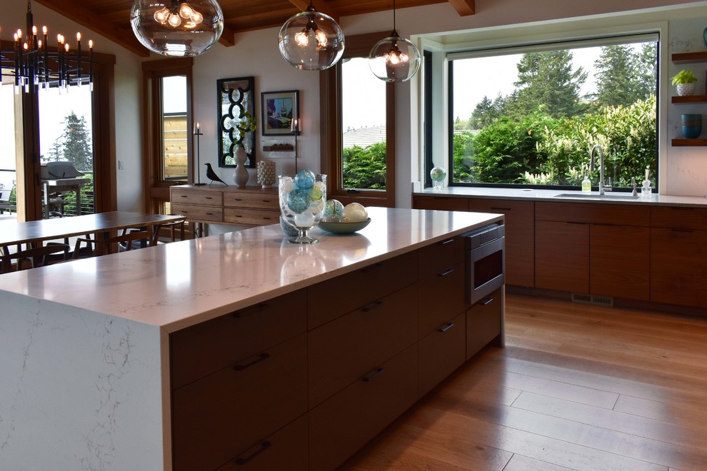 Photo of a midcentury l-shaped kitchen in Seattle with flat-panel cabinets, medium wood cabinets, quartzite benchtops, white splashback, light hardwood floors, with island, grey floor and white benchtop.