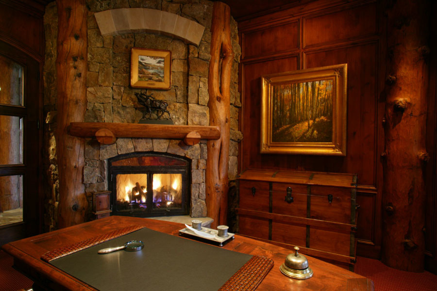 Large country study room in Denver with carpet, a corner fireplace, a stone fireplace surround, a freestanding desk and red floor.