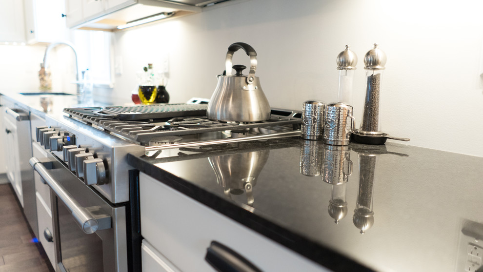 Example of a mid-sized transitional l-shaped dark wood floor open concept kitchen design with an undermount sink, shaker cabinets, white cabinets, granite countertops, gray backsplash, stainless steel appliances and an island