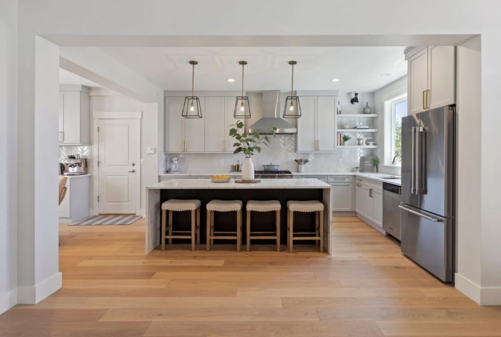 Expansive transitional l-shaped eat-in kitchen in Seattle with an undermount sink, shaker cabinets, grey cabinets, quartz benchtops, white splashback, ceramic splashback, stainless steel appliances, light hardwood floors, with island, beige floor and white benchtop.