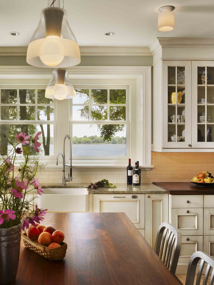 Design ideas for a traditional l-shaped kitchen in Philadelphia with a farmhouse sink, raised-panel cabinets, white cabinets, white splashback, subway tile splashback, stainless steel appliances, cork floors and with island.