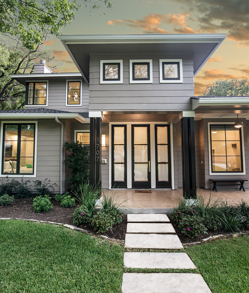 Photo of a transitional two-storey grey exterior in Austin with wood siding.