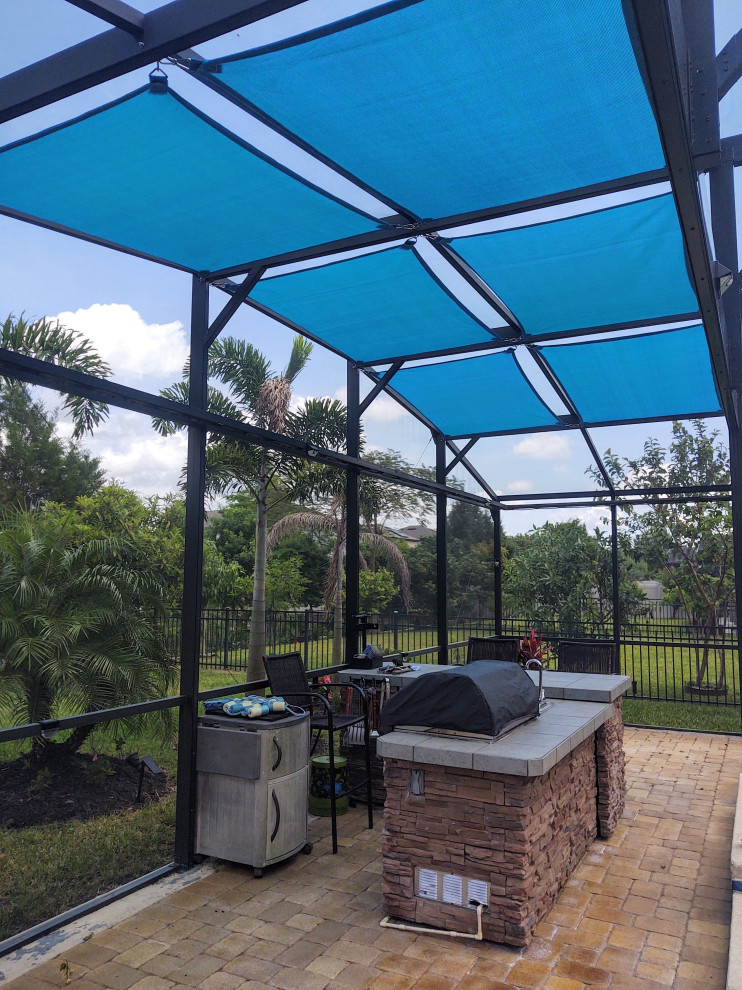 Contemporary backyard patio in Orlando with an outdoor kitchen, brick pavers and an awning.
