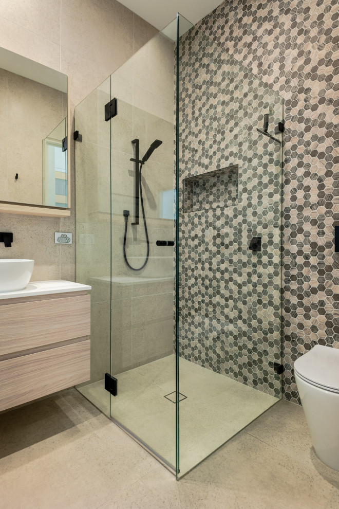 Inspiration for a contemporary 3/4 bathroom in Sydney with flat-panel cabinets, light wood cabinets, a curbless shower, a one-piece toilet, multi-coloured tile, mosaic tile, a vessel sink, beige floor, a hinged shower door and white benchtops.