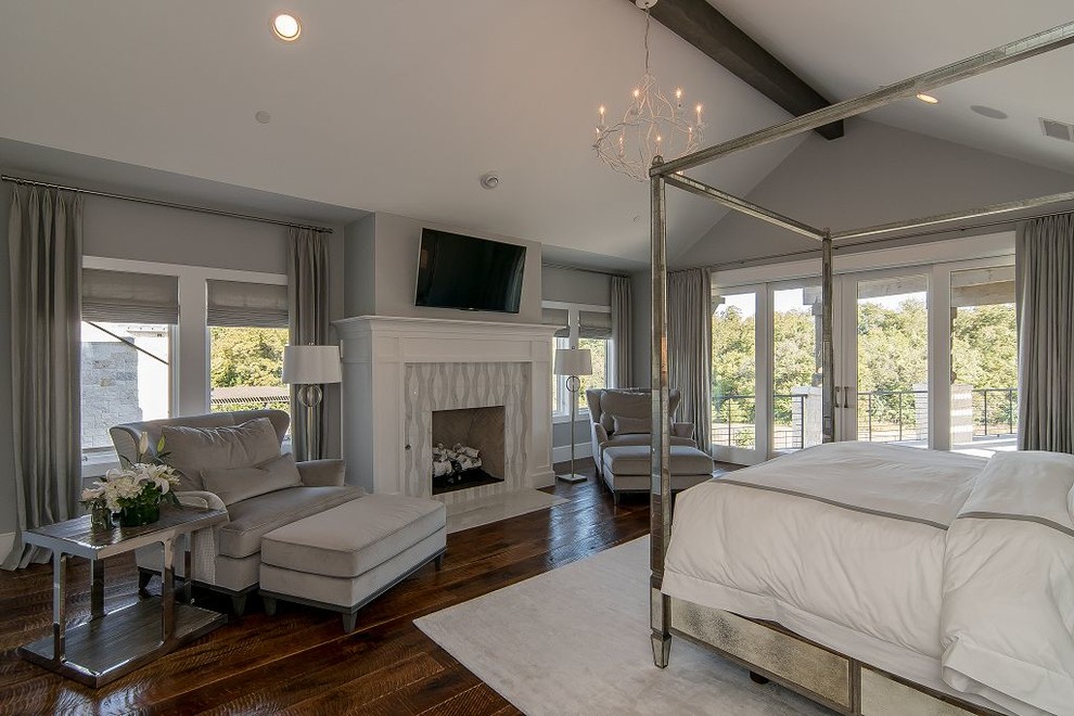 Inspiration for an expansive transitional master bedroom in Dallas with grey walls, dark hardwood floors, a standard fireplace, a tile fireplace surround and brown floor.