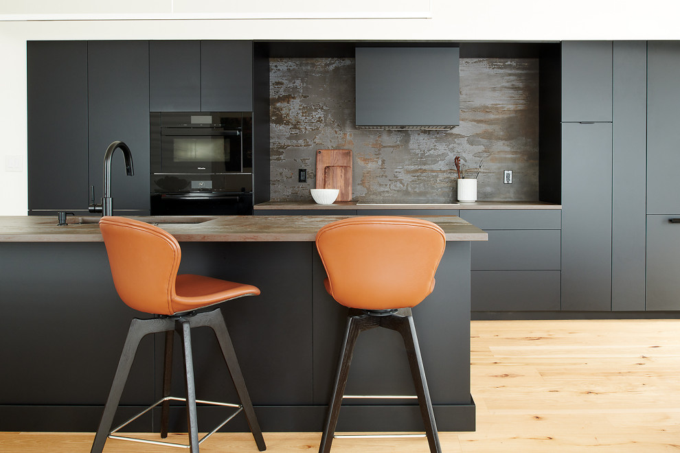 Photo of a mid-sized contemporary single-wall eat-in kitchen in Philadelphia with an undermount sink, flat-panel cabinets, black cabinets, quartzite benchtops, multi-coloured splashback, black appliances, bamboo floors, with island, brown floor, multi-coloured benchtop and vaulted.
