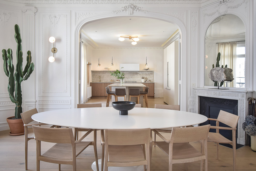 Immagine di una grande sala da pranzo aperta verso il soggiorno contemporanea con pareti bianche, parquet chiaro e boiserie