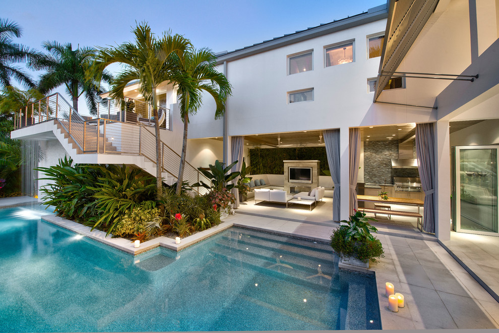 Mid-sized beach style backyard custom-shaped pool in Miami with a hot tub and concrete pavers.