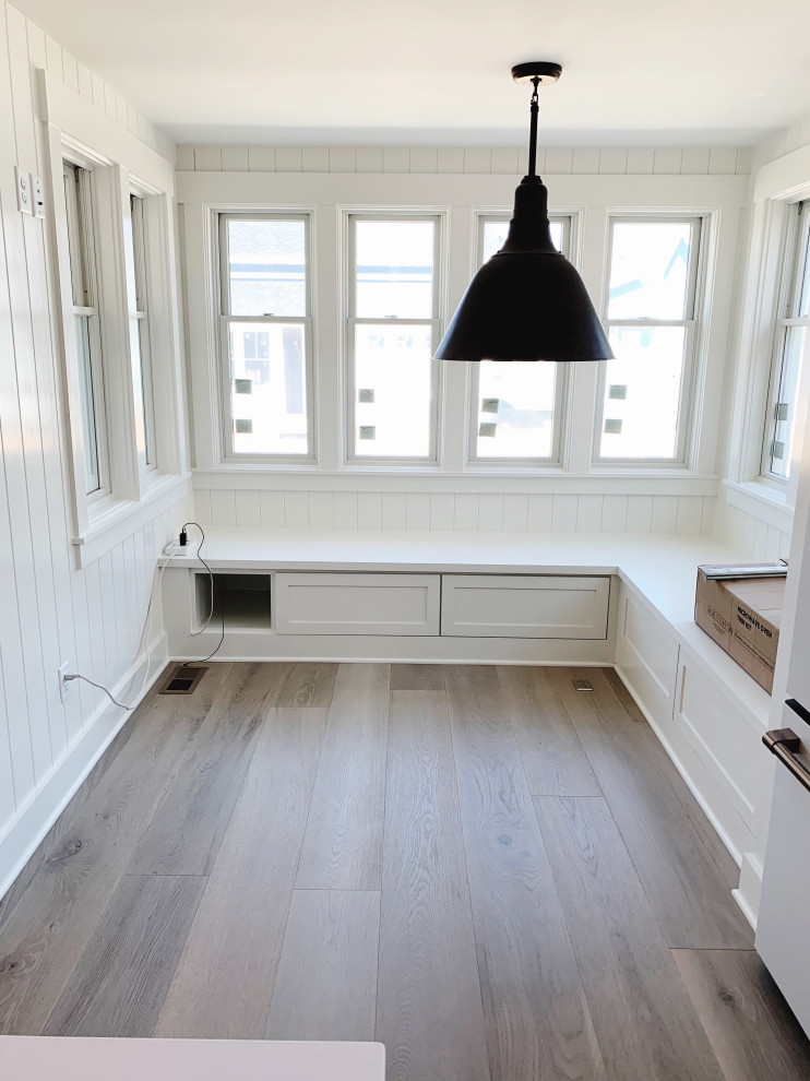 Inspiration pour une petite salle à manger craftsman avec une banquette d'angle, un mur blanc, parquet foncé et du lambris de bois.