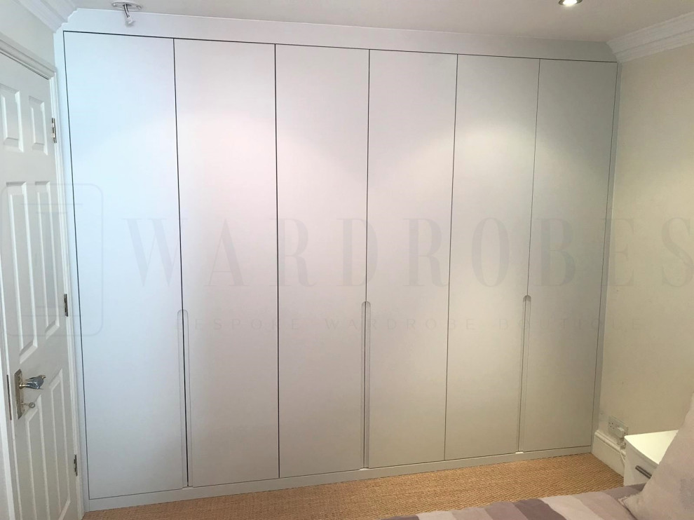 This is an example of a mid-sized contemporary storage and wardrobe in London with white cabinets.
