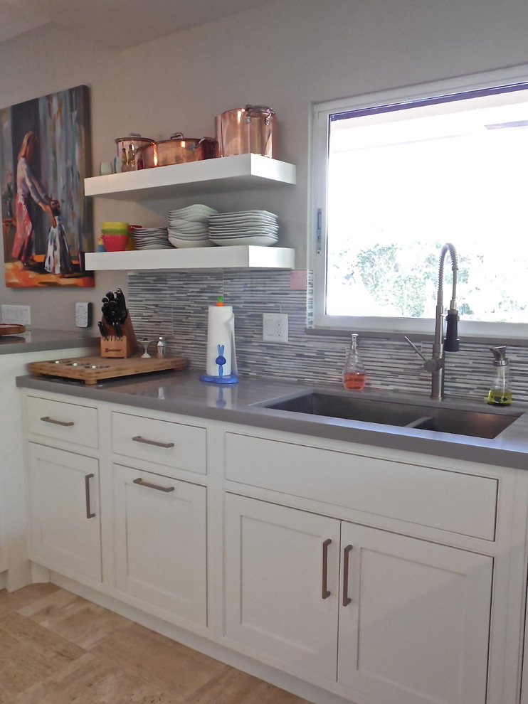 This is an example of a transitional eat-in kitchen in Miami with an undermount sink, beaded inset cabinets, white cabinets, quartz benchtops, grey splashback and stainless steel appliances.