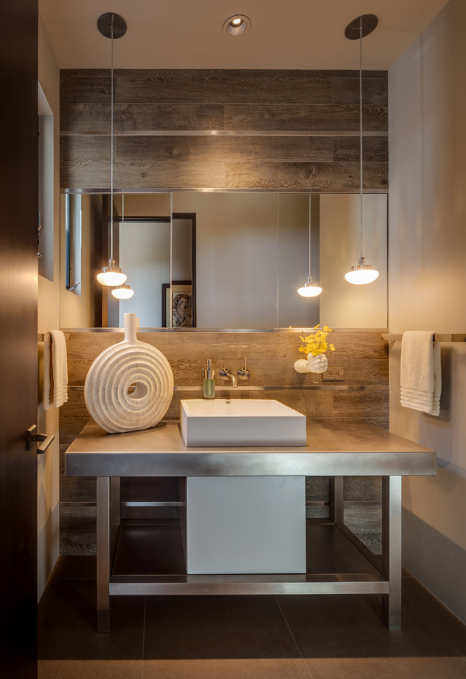 Mid-sized contemporary kids bathroom in Phoenix with open cabinets, medium wood cabinets, a one-piece toilet, brown tile, porcelain tile, white walls, porcelain floors, an integrated sink, stainless steel benchtops and beige floor.