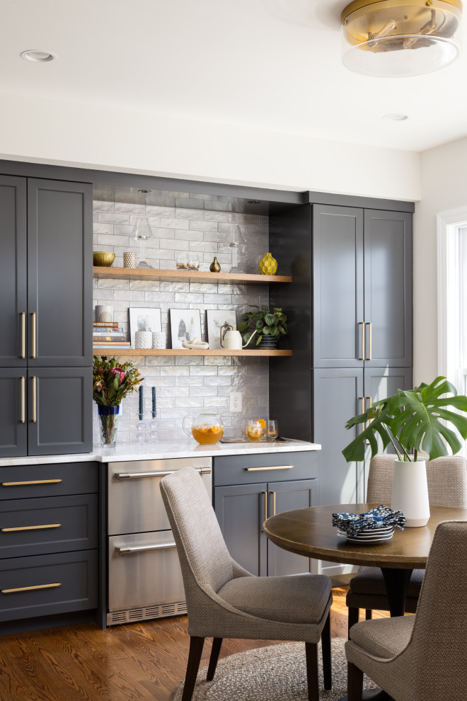 Inspiration for a large transitional l-shaped eat-in kitchen in DC Metro with a farmhouse sink, shaker cabinets, grey cabinets, grey splashback, ceramic splashback, stainless steel appliances, medium hardwood floors, with island, brown floor, grey benchtop and quartzite benchtops.