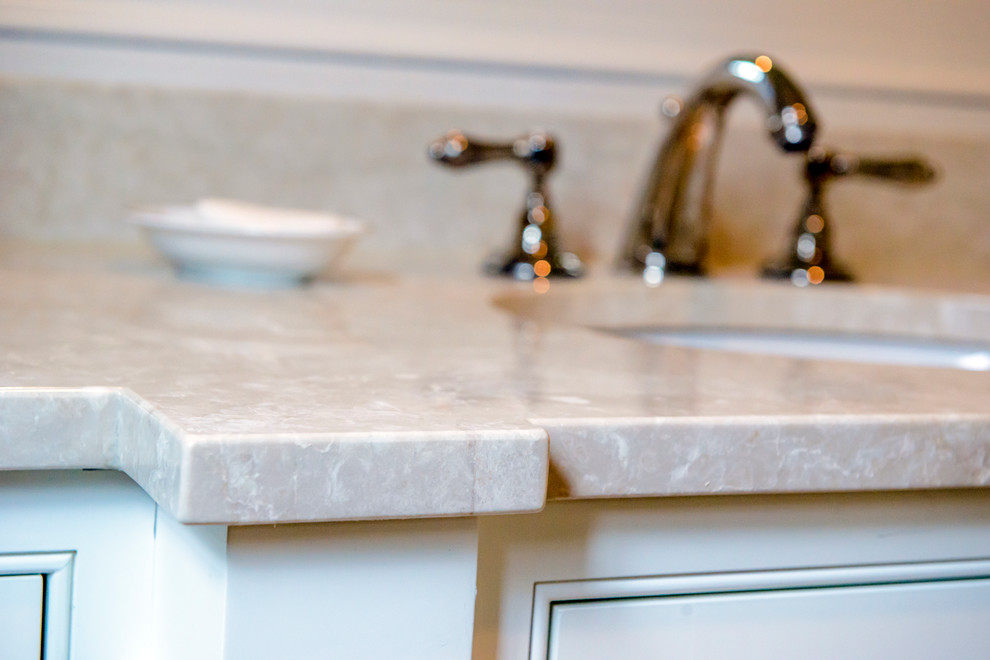 Drop-in bathtub - traditional beige tile marble floor drop-in bathtub idea in Atlanta with marble countertops, blue walls and an undermount sink